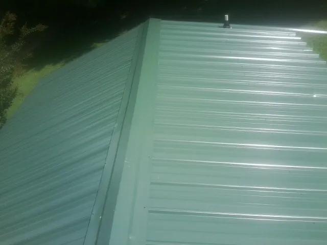 New green metal panels meeting at the ridge of a roof — Flat Roof Repair work by our crew in Byron
