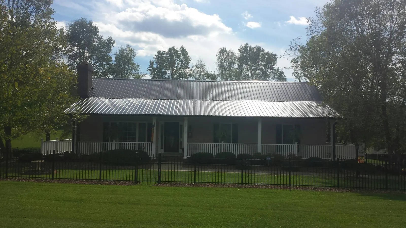 Gray metal roof on a brick ranch with a full width front porch — Gutter Guard Installation work by our crew in Byron